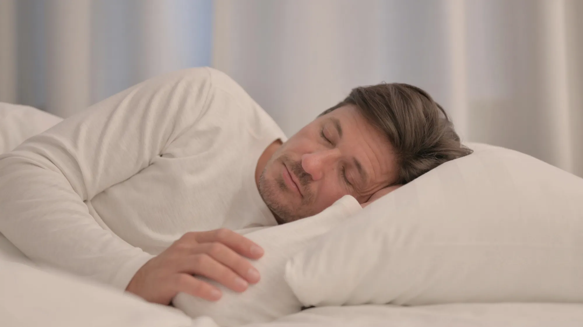 adult man sleeping on his side, experiencing shoulder pain